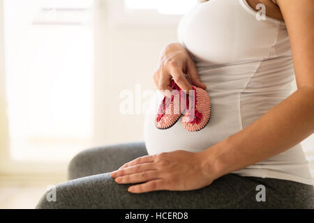 Donna incinta tenendo poco scarpe neonato Foto Stock