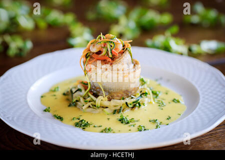 Rotolo di pesce con gamberi e salsa cremosa, erbe Verdure su una piastra bianca Foto Stock