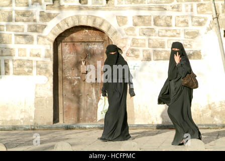 Sana, Yemen - 19 Gennaio 2008: le donne indossano il burqa e camminare sulla strada della vecchia Sana, Yemen Foto Stock