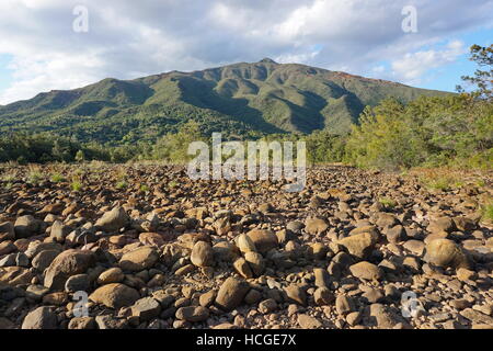 Riverbed secco con rocce e una montagna di background, Nuova Caledonia, Dumbea river, Grande Terre, l'isola del Sud Pacifico Foto Stock