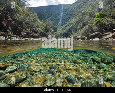 Fiume al di sopra e al di sotto della superficie dell'acqua con rocce su riverbed subacquea, Dumbea river, Nuova Caledonia Foto Stock