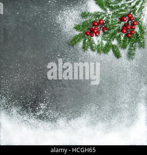 Rami di pino con bacche rosse nella neve. Vacanze di Natale sfondo. In stile vintage tonica foto Foto Stock