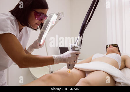 Medico di eseguire la depilazione laser femmina sulla pelle del paziente Foto Stock