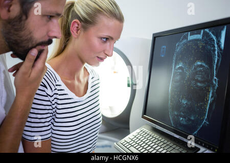 Donna che guarda MRI scan relazione sullo schermo del computer Foto Stock