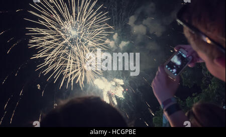 Donna godendo di fuochi d'artificio di celebrazione e di scattare foto Foto Stock