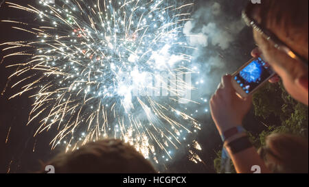 Donna godendo di fuochi d'artificio di celebrazione e di scattare foto Foto Stock