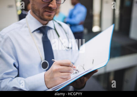 Medico a scrivere una relazione medica Foto Stock