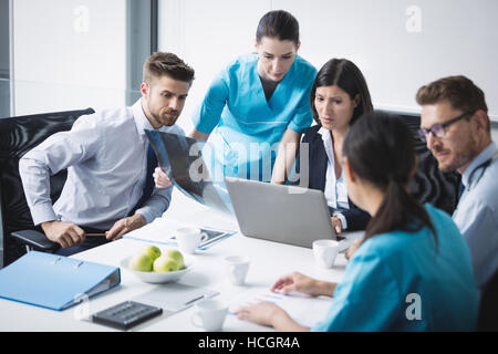 Il team medico di discutere su laptop in riunione Foto Stock