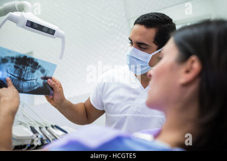 Giovane maschio dentista esaminando X-ray con il paziente femmina Foto Stock