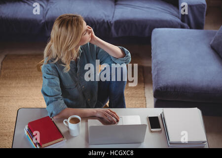 Premurosa donna utilizzando laptop in salotto Foto Stock