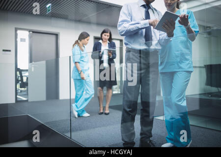 I medici e gli infermieri a discutere su tavoletta digitale Foto Stock