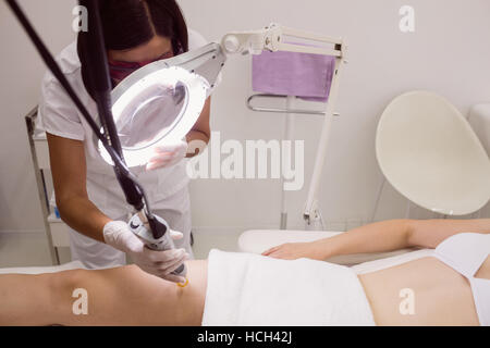 Medico di eseguire la depilazione laser femmina sulla pelle del paziente Foto Stock