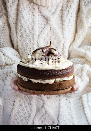 Donna di mani tenendo una torta al cioccolato Foto Stock