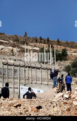 Nablus, West Bank, Territorio palestinese. Il 9 dicembre, 2016. I dimostranti palestinesi scagliare sassi verso forze di sicurezza israeliane durante scontri a seguito di una dimostrazione contro l'espropriazione delle terre palestinesi da parte di Israele nel villaggio di Kfar Qaddum, nei pressi di Nablus, nei territori occupati della Cisgiordania il 9 dicembre 2016 Credit: Nedal Eshtayah APA/images/ZUMA filo/Alamy Live News Foto Stock