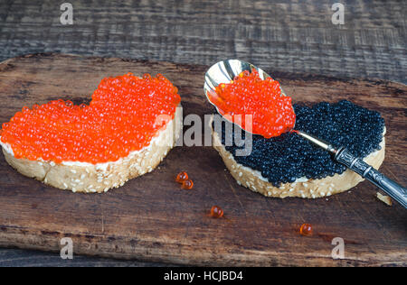 Panini con caviale in a forma di cuore sul tagliere di legno e di sfondo. Foto Stock