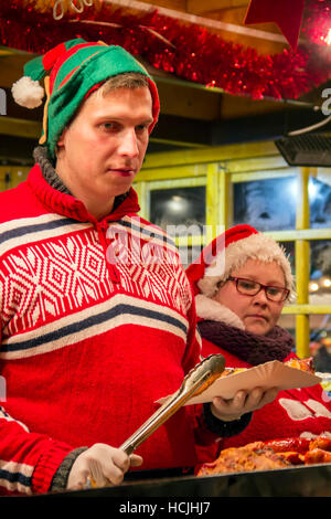 GDANSK, Polonia - 4 dicembre: Uomo vende salumi e carni alla griglia in inverno Mercatino di Natale Foto Stock