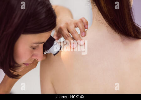 Il dermatologo esaminando la pelle del paziente con dermatoscope Foto Stock