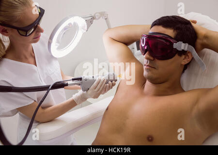 Medico di eseguire la depilazione laser maschio sulla pelle del paziente Foto Stock