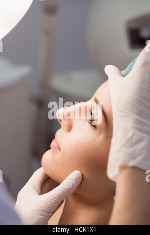 Medico esaminando womans volto per il trattamento cosmetico Foto Stock