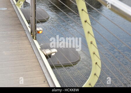 In prospettiva laterale di un moderno ponte metallico della ringhiera con piccole luci di colore arancione Foto Stock