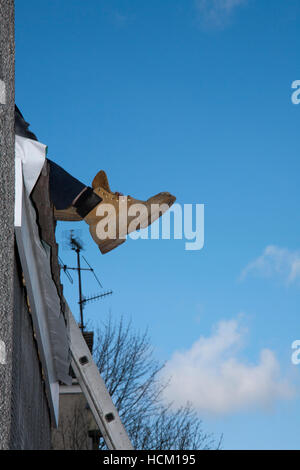 Builder's stivali a strapiombo mentre si lavora sul tetto Foto Stock