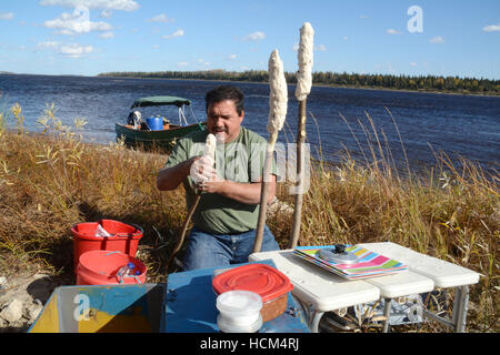 Un uomo indigeni rendendo bannock su un bastone, nativo North American food simile al pane, nel nord Ontario, Canada. Foto Stock