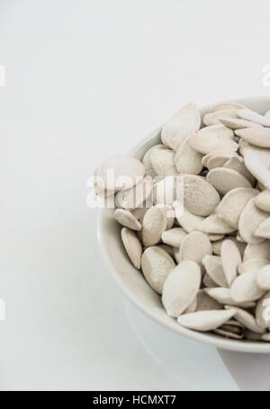 I semi di zucca in una ciotola su sfondo bianco Foto Stock