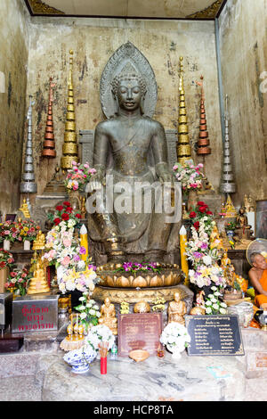 Statua di un Buddha scolpito in pietra nera nella postura europea , seduti su una sedia con le mani sulle ginocchia e entrambi i piedi sulla terra, in Ayuttha Foto Stock