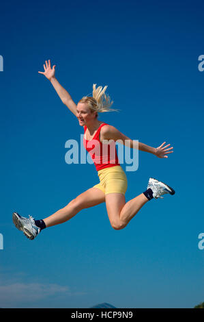Giovane donna bionda jumping, gioiosa Foto Stock