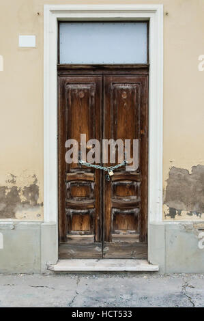 Porta di legno bloccata da un lucchetto con catena Foto Stock