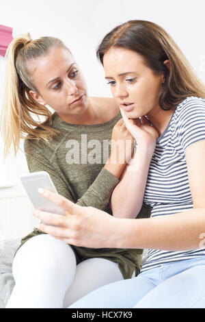 Ragazza con un amico di essere vittima di bullismo mediante messaggio di testo Foto Stock