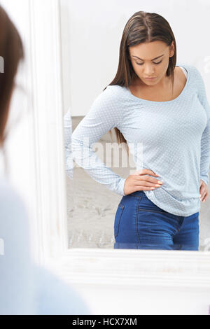 Infelice ragazza adolescente guardando il riflesso dello specchio Foto Stock