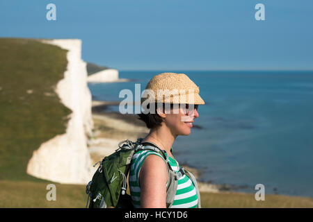 Una donna si affaccia sulla scogliera vicino Beachy Head con vedute delle Sette sorelle, South Downs National Park, East Sussex, Regno Unito Foto Stock