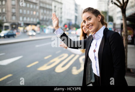 Le donne d'affari salutando taxi sulla strada Foto Stock