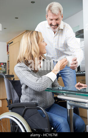 Portare l uomo donna in carrozzella bevanda calda a casa Foto Stock