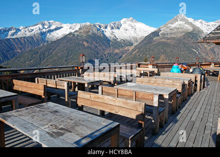 Ristorante esterno in montagna immagine con la terrazza di un , circondato dalle montagne delle Alpi, i rustici tavoli di legno pronto per ricevere gli ospiti. Foto Stock