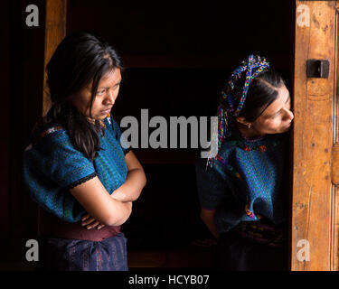 Due donne Maya il peering fuori la porta di Sant Antonio da Padova la chiesa di San Antonio Palopó, Guatemala, indossando abiti tipici del loro paese, Foto Stock