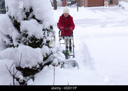 Donna che utilizza eco-friendly Snow Plough aratura è la sua strada in inverno con un sacco di neve fresca in Ontario, Canada Foto Stock