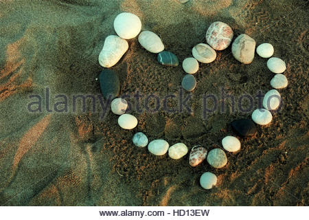 Pietra di ghiaia amore cuore su una spiaggia come Rodi gode di un bel tramonto Foto Stock