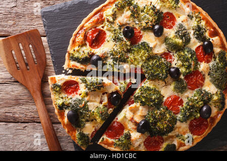 Torta salata con pollo, broccoli, pomodoro e olive vicino sul tavolo. vista orizzontale dal di sopra Foto Stock