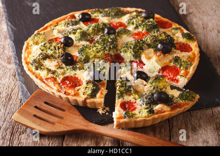 Torta salata con pollo, broccoli, pomodoro e olive vicino sul tavolo orizzontale. Foto Stock