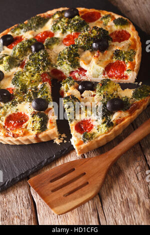 Torta salata: Fette di Quiche con pollo, broccoli, pomodoro e olive vicino sul piano verticale. Foto Stock