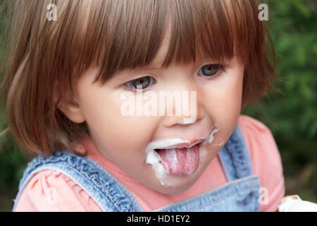 Carino bambina sono mangiare gelato in estate con mettere la lingua di fuori Foto Stock