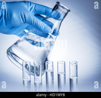 Bicchiere da laboratorio in analyst la mano nel guanto di plastica. Foto Stock