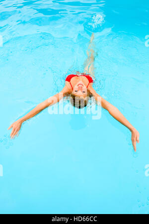 Giovane donna nuoto dorso in un pool Foto Stock