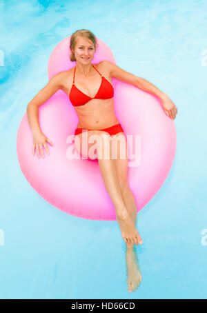 Giovane donna attraente su un airbed in una piscina Foto Stock