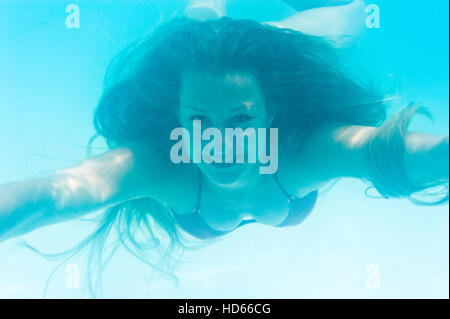 Giovane donna nuotare sotto l'acqua Foto Stock