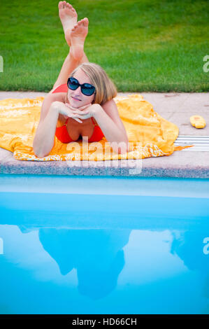 Giovane donna attraente che giace accanto a un pool Foto Stock