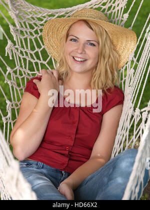 Giovane donna che indossa un cappello di paglia in una amaca Foto Stock