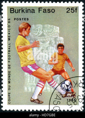 Un timbro stampato in Burkina Faso, dedicato alla Coppa del Mondo FIFA in Messico nel 1986, mostra i giocatori di calcio Foto Stock